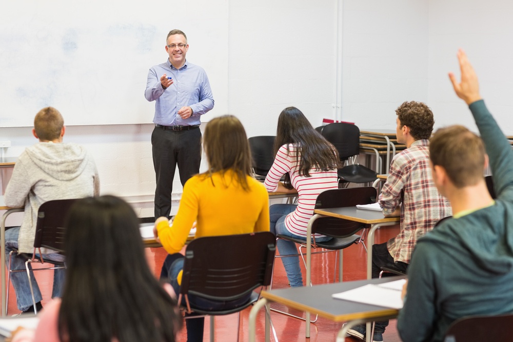 Rear view of students attentively listening to male teacher in the classroom.jpeg