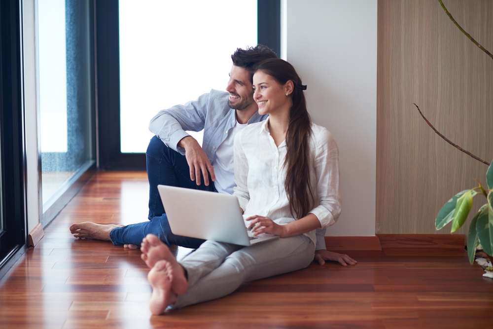 happy young relaxed couple working on laptop computer at modern home interior