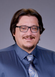 Man with glasses wearing a blue shirt and tie